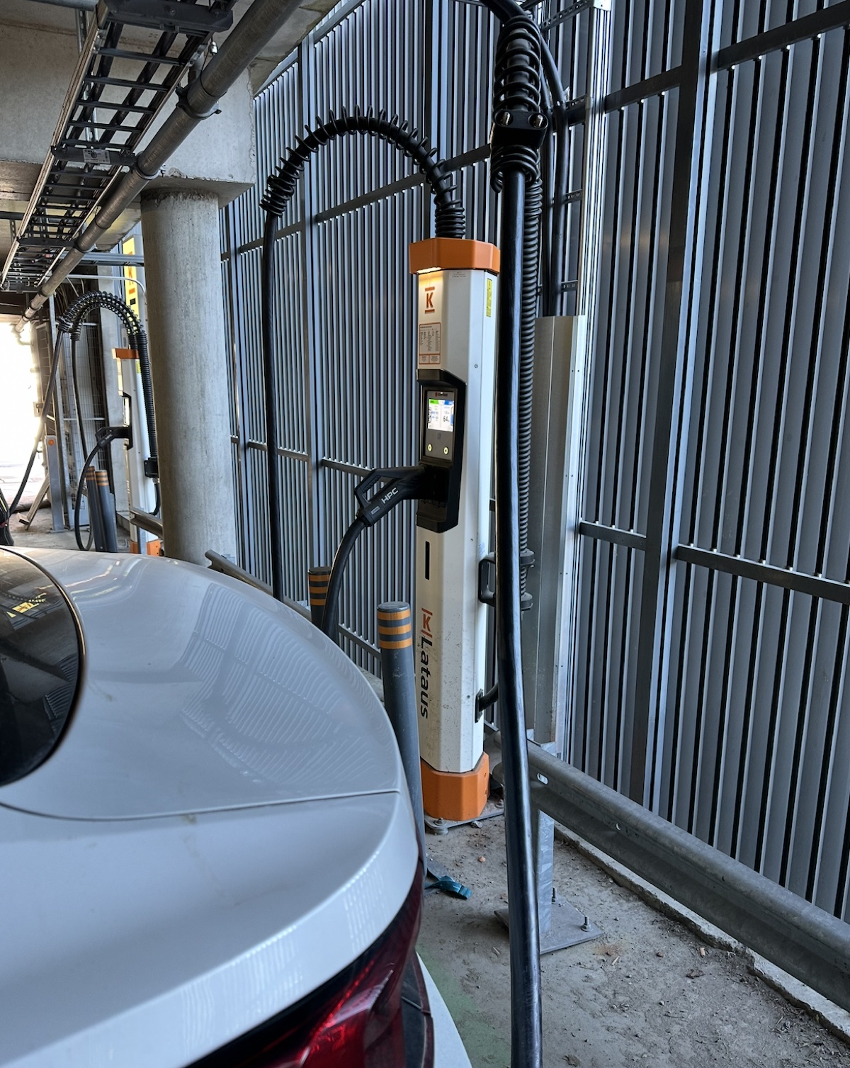 A Kempower Satellite dispenser in an underground car park, with the charging cable connected to an electric car.